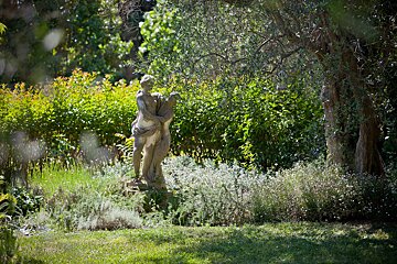 A statue of a woman holding a child in a garden