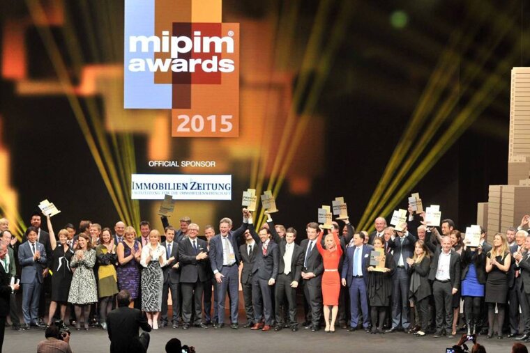 A group of people holding trophies in front of a sign that says mipim awards 2015
