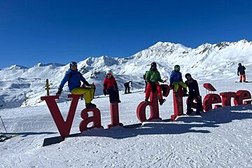 A group of skiers are posing in front of a sign that says val d' isere