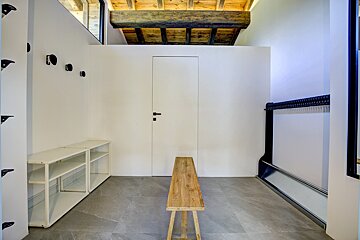A hallway with a wooden bench and a white door