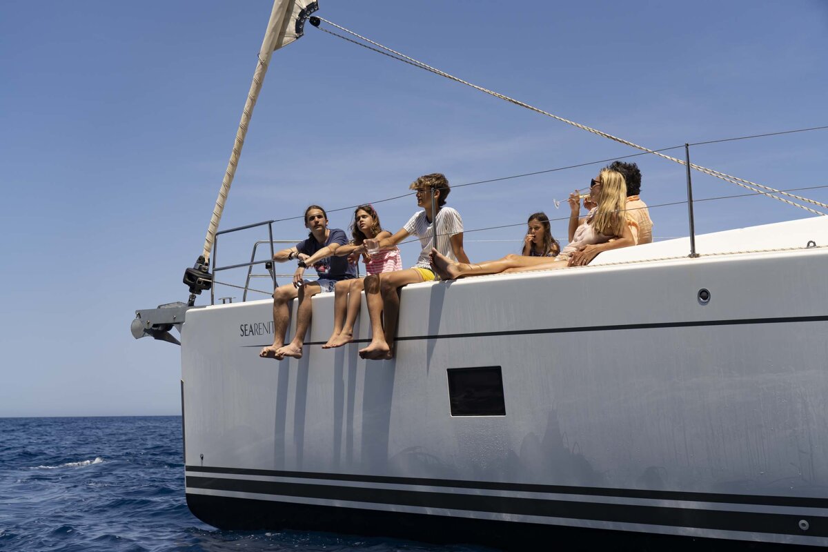 A group of people sitting on the side of a sailboat that says serenity