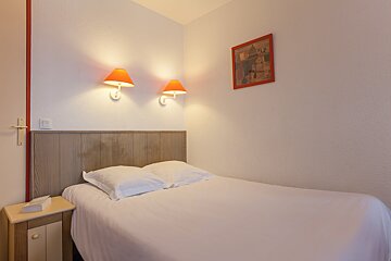A bedroom with a picture on the wall above the bed
