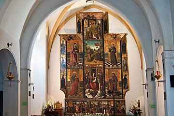 The inside of a church with a large painting on the wall
