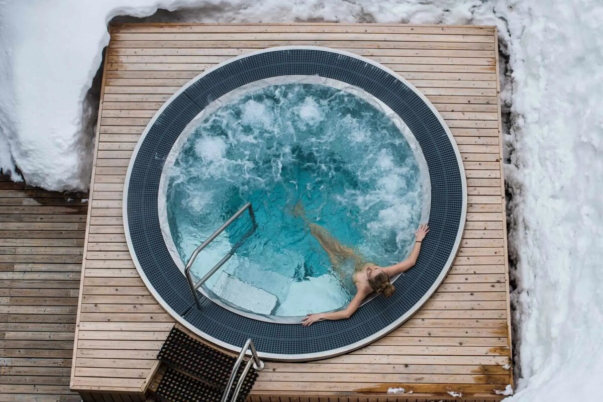 A woman is laying in a hot tub surrounded by snow