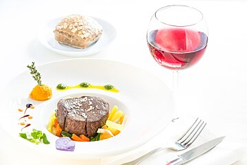 A plate of food next to a glass of wine