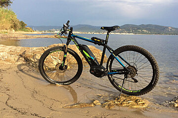 A black and blue bicycle is parked on a rocky beach