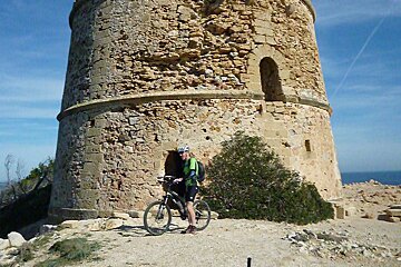 a mountain biker next to a watch tower in mallorca