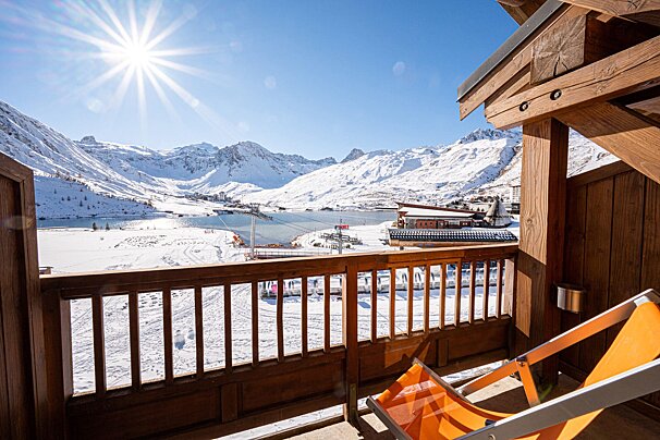 A chair on a balcony overlooking a snowy mountain range
