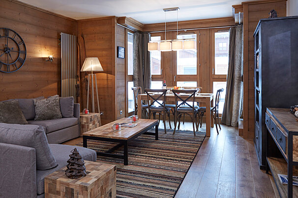 A living room with a clock on the wall that has roman numerals