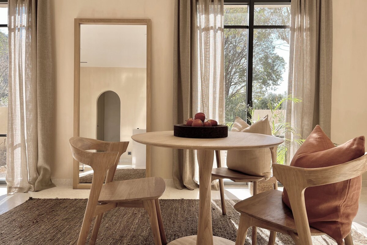 A room with a table and chairs and a large mirror