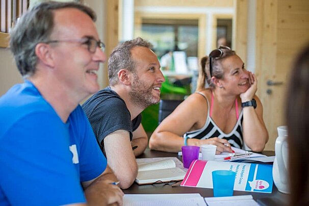 A group of people are sitting at a table with a book on it that says ' english grammar ' on it