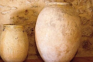 Two large vases are sitting next to each other in front of a stone wall