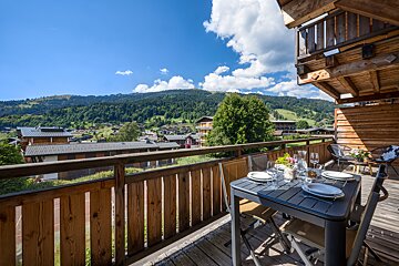 A table and chairs on a balcony overlooking a mountain range