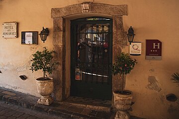 A sign for hotel les armoiries hangs above a doorway