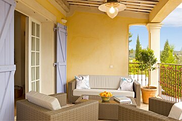 A patio with a couch and chairs with a bowl of oranges on the table