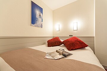 A bed with red pillows and a magazine that says spa on it