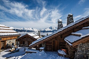 A snowy cabin with mountains in the background