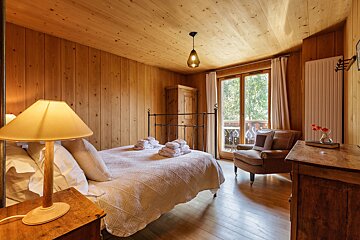 A bedroom with wood paneling and a bed and chair