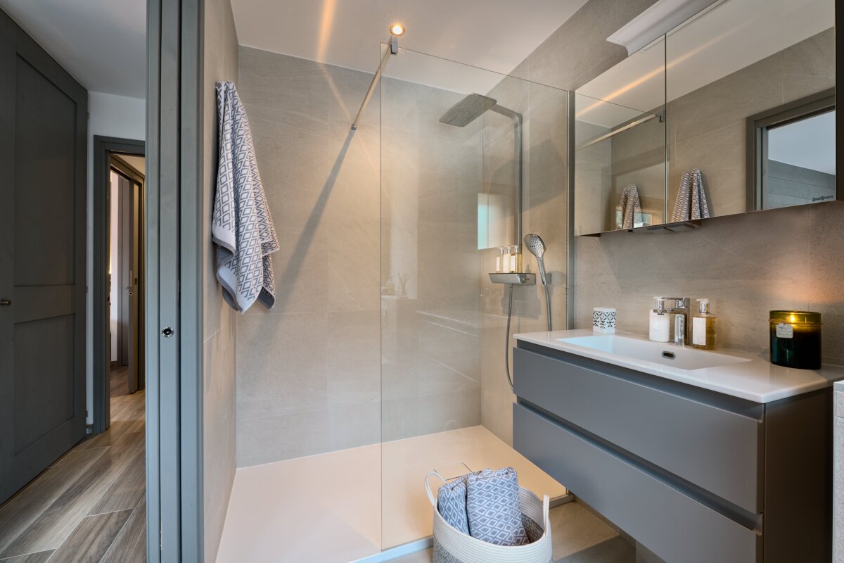 A bathroom with a walk in shower and a sink