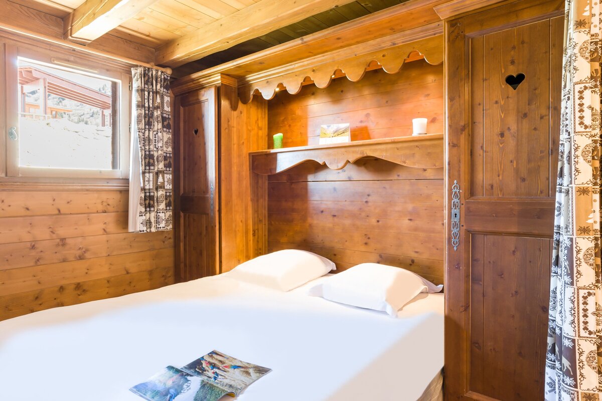 A wooden bedroom with a bed and a window