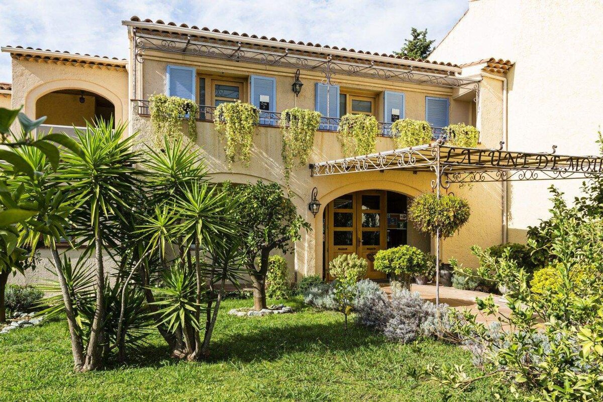 A yellow house with blue shutters and a pergola
