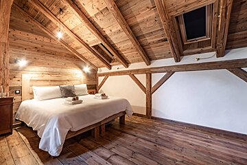 A bedroom with a wooden ceiling and a large bed
