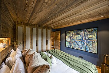A bedroom with a large painting on the wall above the bed