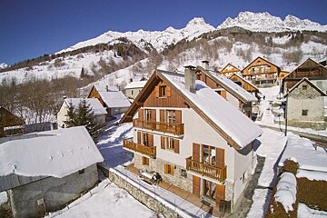 A snowy house with mountains in the background