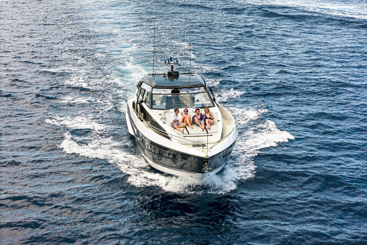 A group of people sit on the back of a boat in the ocean