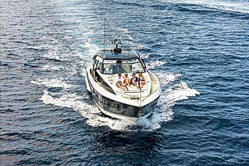 A group of people sit on the back of a boat in the ocean