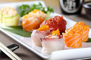 A plate of sushi with a bottle of sake in the background