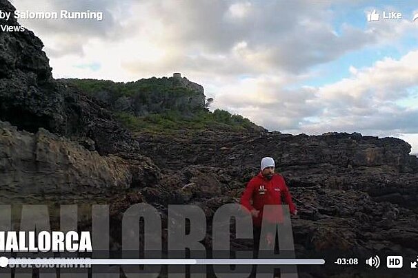 A salomon running video shows a man walking on a rocky cliff