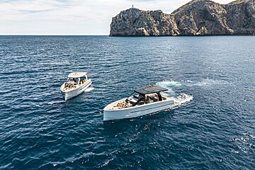 Two boats are floating in the ocean with a mountain in the background