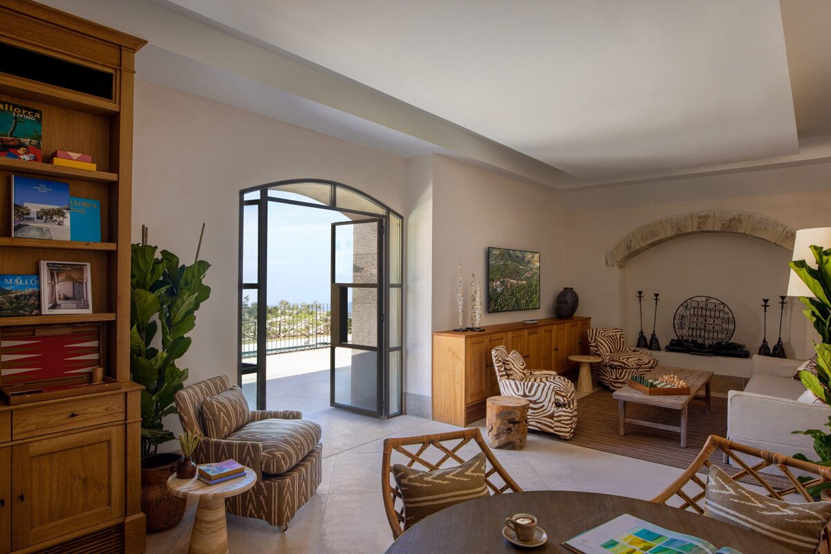 A living room with a table and chairs and a bookshelf with a blue book titled mediterranean