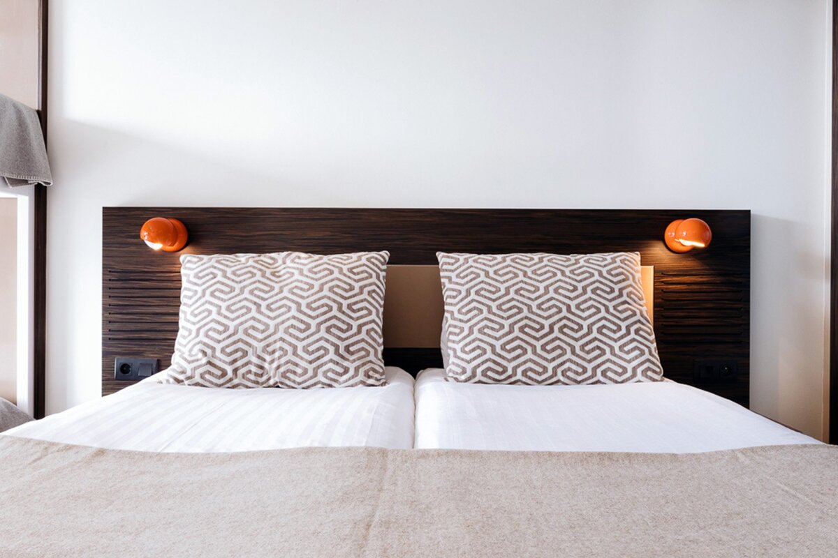 A bed with two pillows on it and a wooden headboard