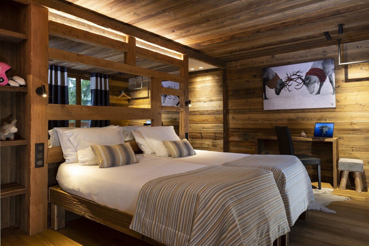 A bedroom with two beds and a picture of reindeer on the wall