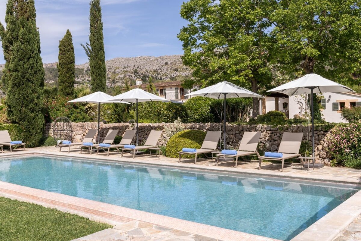 A large swimming pool surrounded by chairs and umbrellas