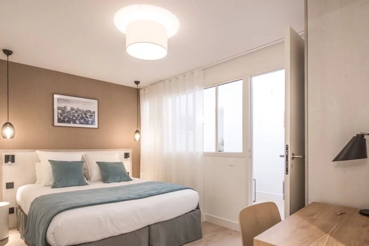 A hotel room with a bed and a desk