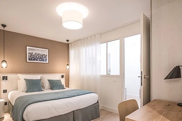 A hotel room with a bed and a desk