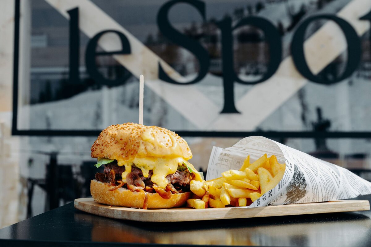 A hamburger and french fries on a cutting board in front of a sign that says le spo