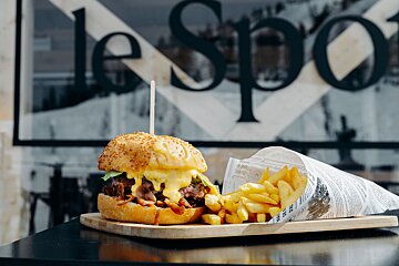 A hamburger and french fries on a cutting board in front of a sign that says le spo