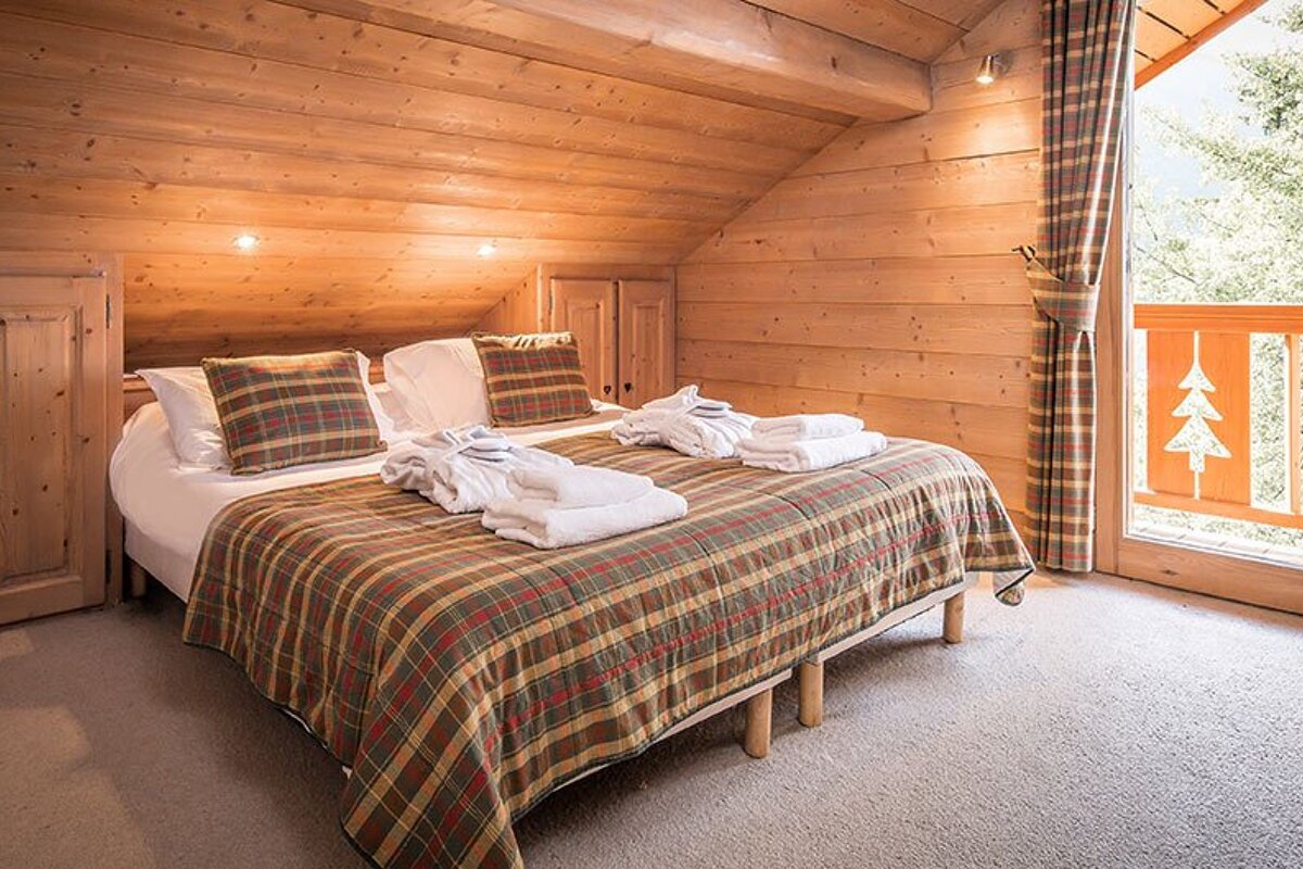 A bed with a plaid blanket and pillows in a wooden room