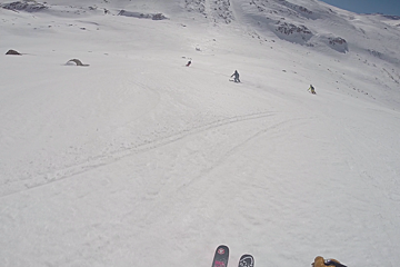 a small group of skiers in an empty off piste bowl