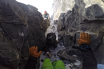 skiers climbing down a rocky chute