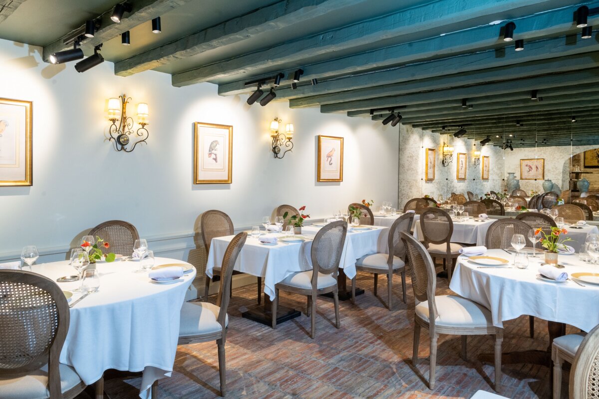 A dining room with tables and chairs and paintings on the wall