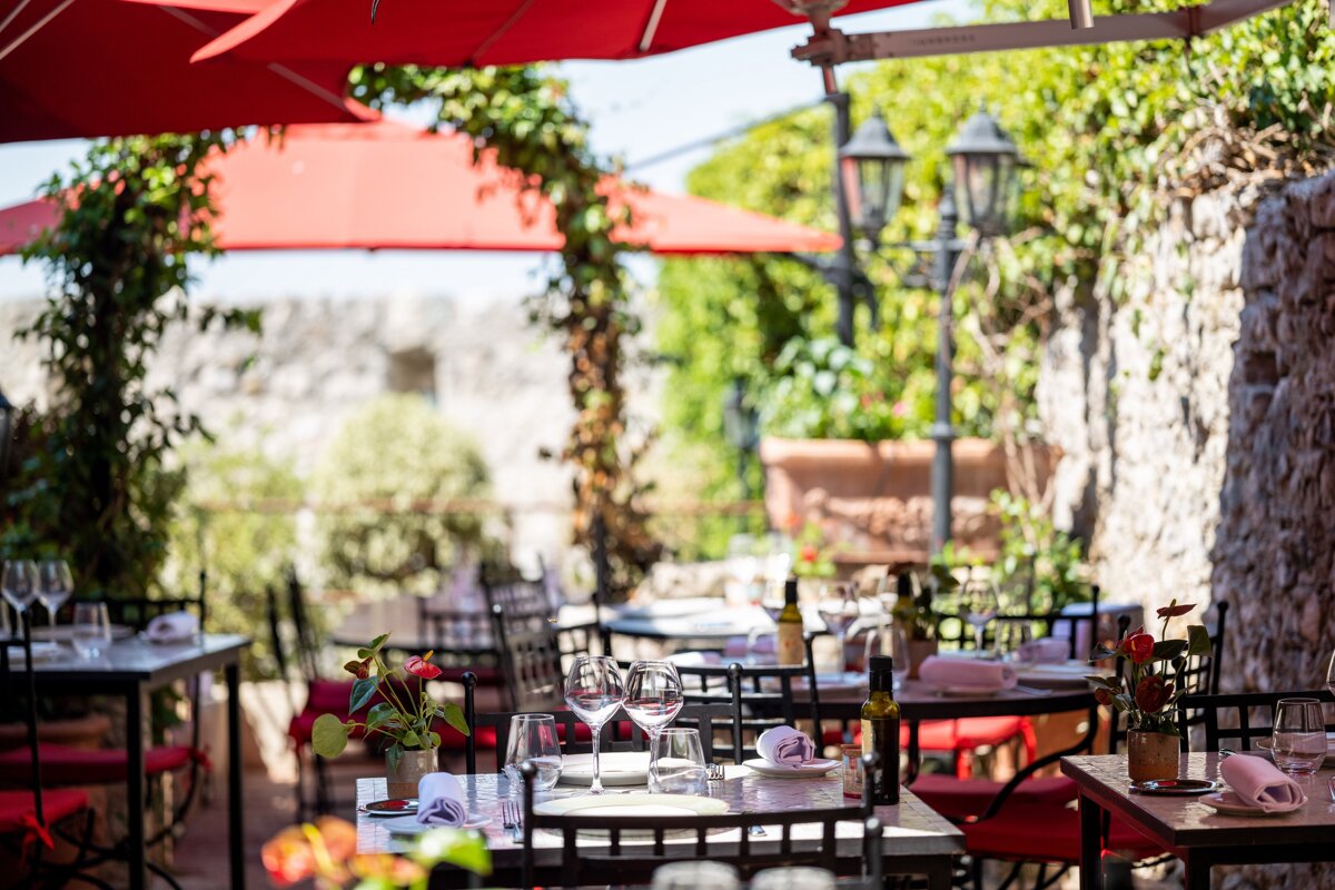 A restaurant with red umbrellas and tables and chairs