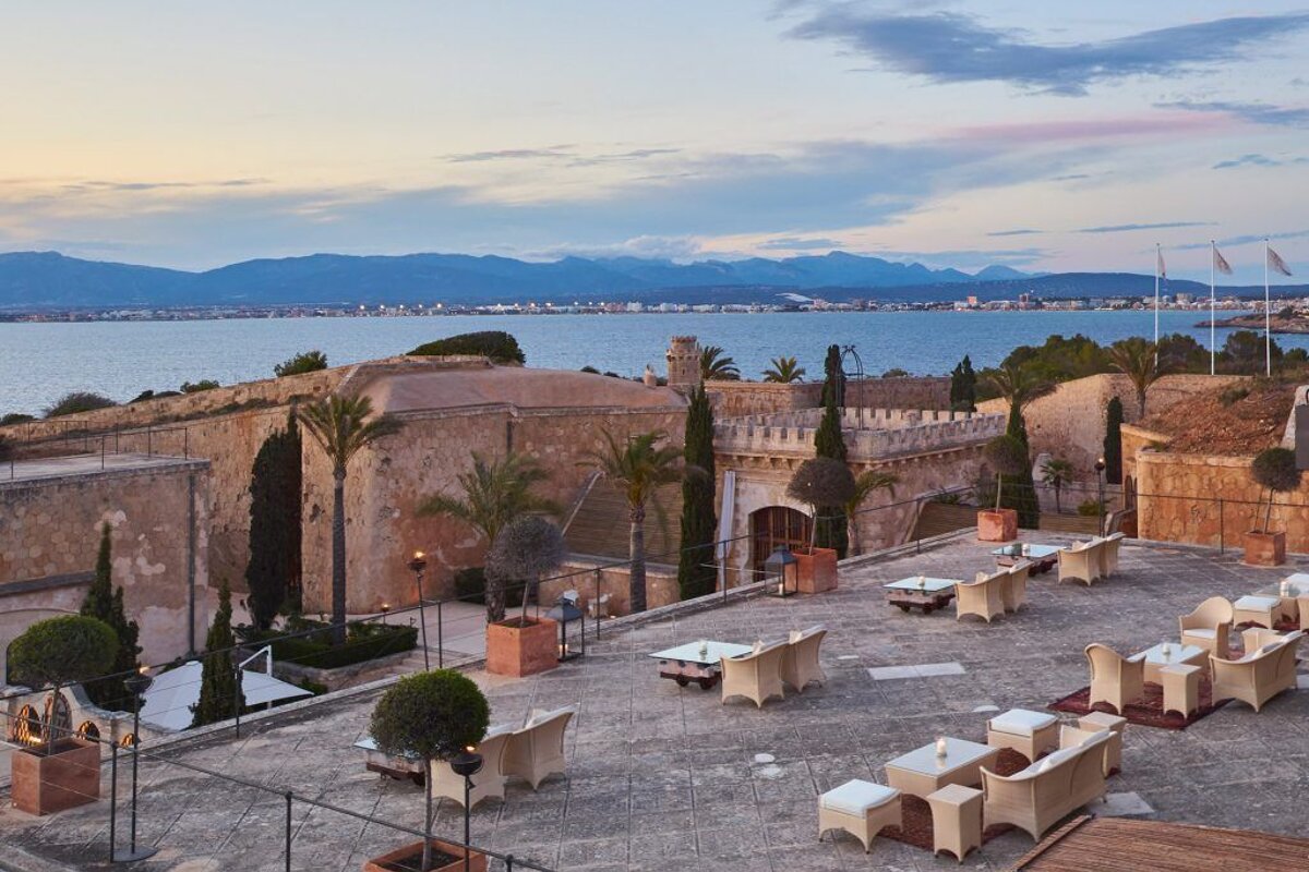 A patio with tables and chairs in front of a building overlooking the ocean
