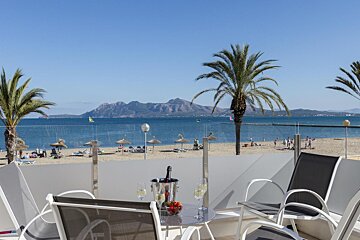 A bottle of champagne sits on a table in front of a beach