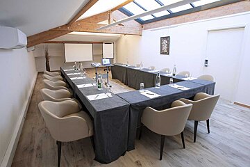 A conference room with tables and chairs and a projector screen