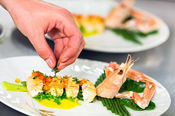 A person is preparing a plate of food with shrimp and green beans